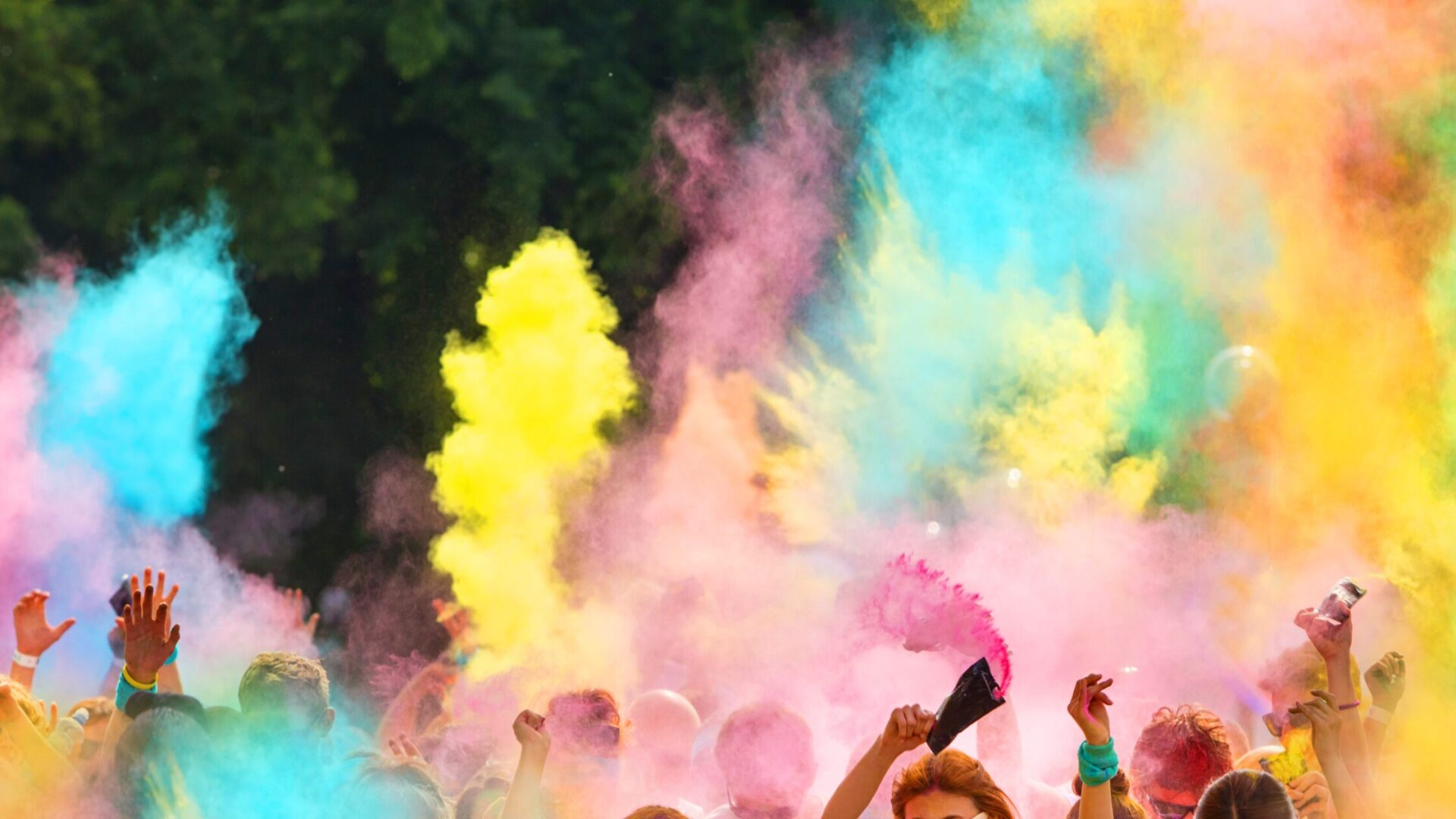 A group of people throwing multiple colors of chalk dust into the hair.