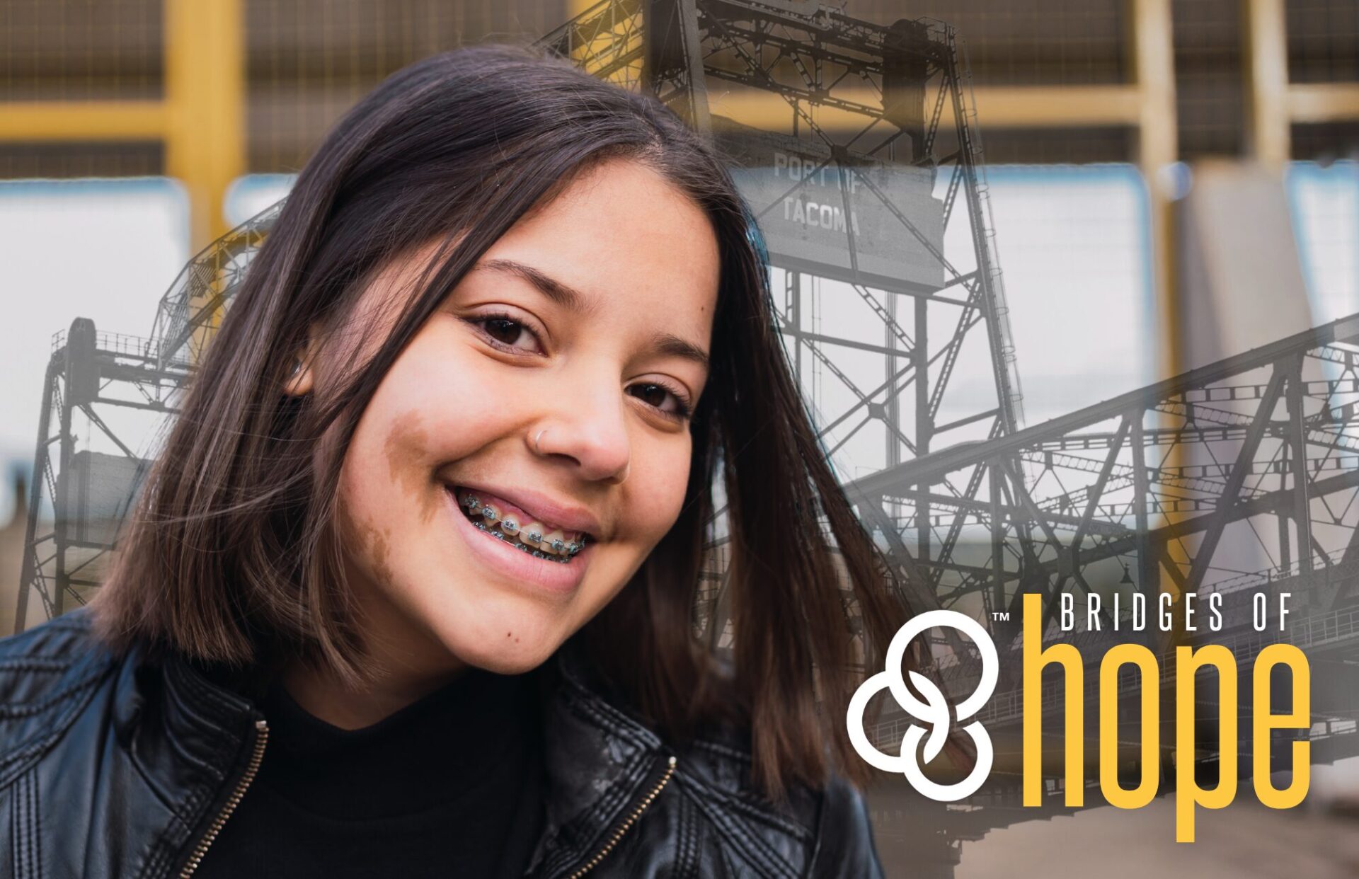 Sydney, a teen age girl, smiles at the camera with a faded image of Tacoma's Murray Morgan Bridge behind her and the Bridges of Hope title and YFC three rings logo in the bottom right corner.